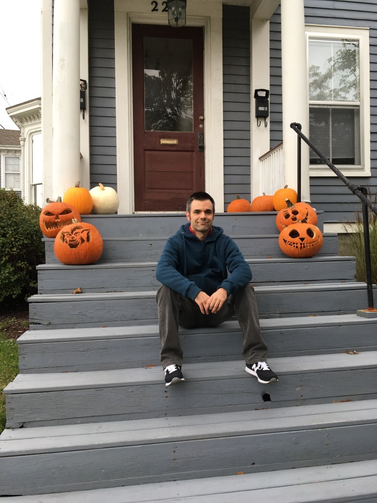 Sentado en la escalera rodeado por calabazas