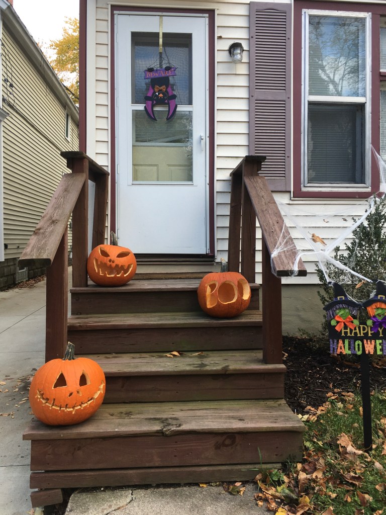 Tres calabazas sonrientes en la escalera de una casa