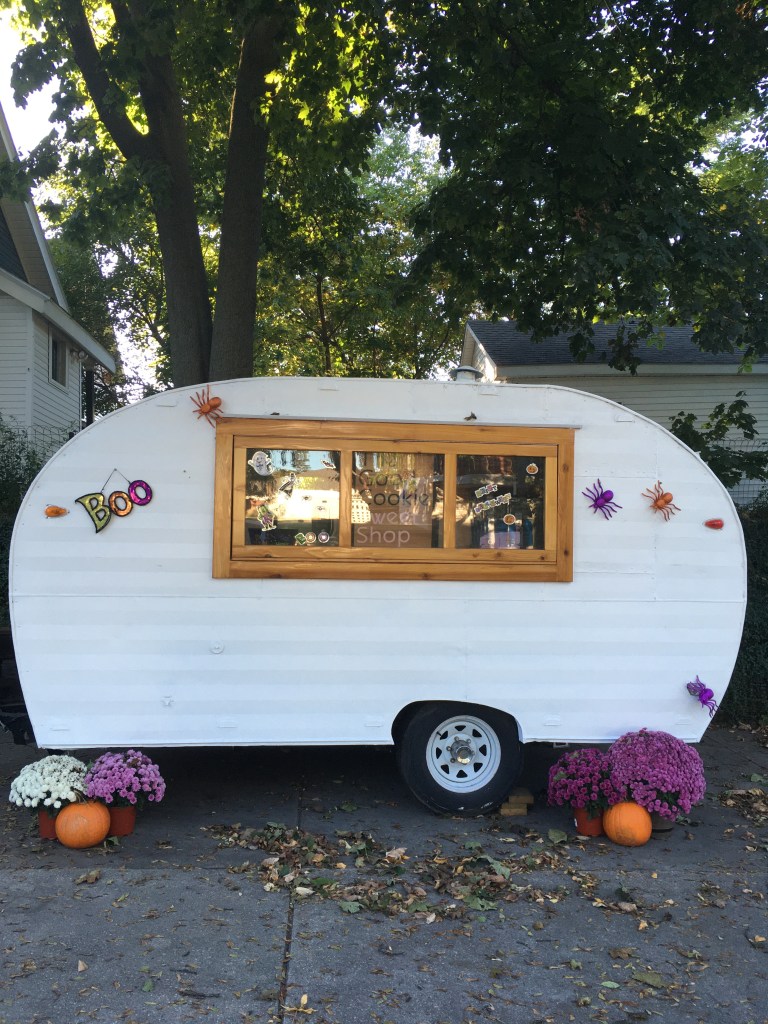 Una caravana blanca adornada con arañas y calabazas